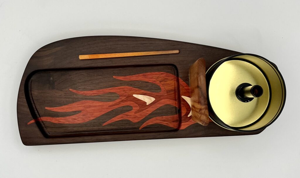 The Roadster Flame features a decorative red flame wooden tray holding a rectangular plate, thin chopstick, small wooden stand, and round golden-lidded bowl, all neatly arranged on a white background.
