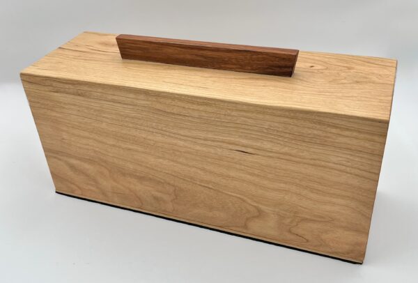 Hideaway is a rectangular wooden box featuring smooth, light wood grain surfaces and a contrasting dark handle on top, displayed against a plain white background.