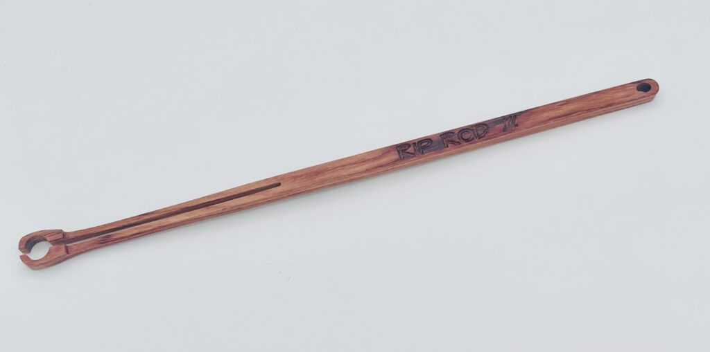 A handcrafted wooden stick with a notched end, possibly a tool or utensil, engraved with "RIP RCD '17" near the handle, displayed on a plain white background.