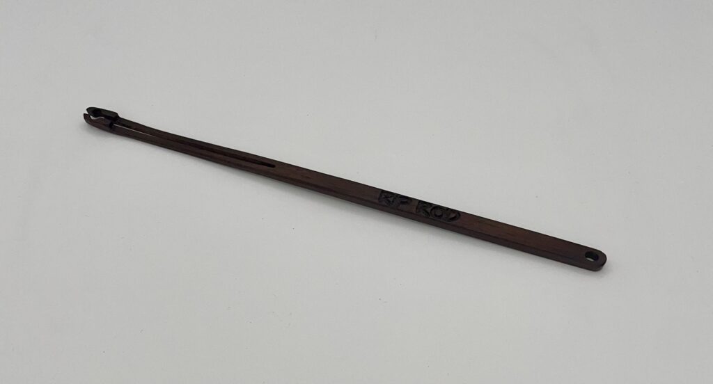 A long, thin, dark brown "Tropical Walnut" wooden shoehorn with a slot at one end and "RE-ROD" engraved on the handle, placed on a plain white background.