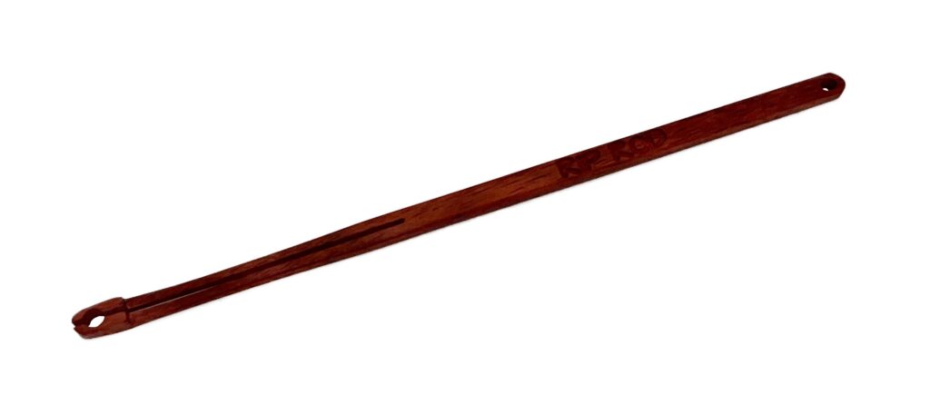The Paduk is a single reddish-brown wooden hair stick featuring a rounded end and a small hole near the tip, shown on a white background.